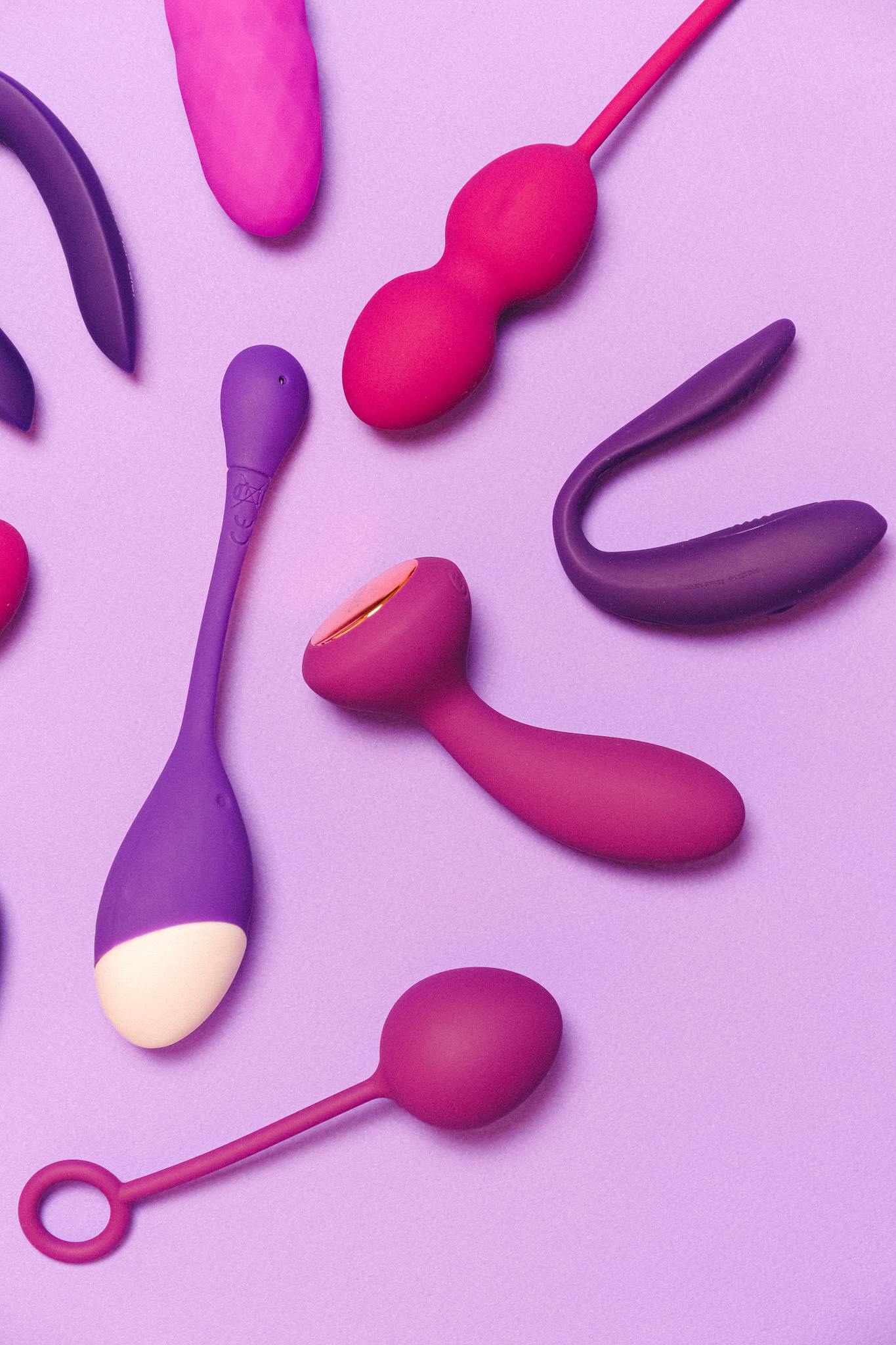A variety of colorful silicone sex toys on a purple background showcasing modern pleasure products.